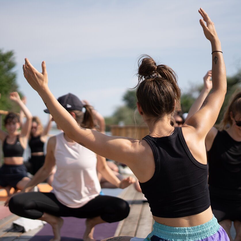 Un gruppo di persone partecipa a un corso di yoga su una zattera sul fiume Mur a Graz, organizzato da “Der Flößerei”. | © Robert Supnig