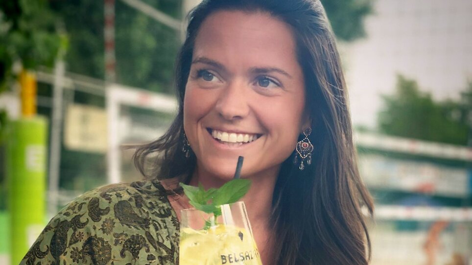 A woman holding a drink, smiling at Mur Beach in Graz. | © Mur Beach - Ingo Gruber