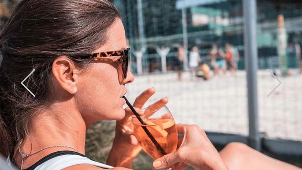 Relaxed woman on the beach volleyball court with a drink in her hand. | © Mur Beach - Ingo Gruber