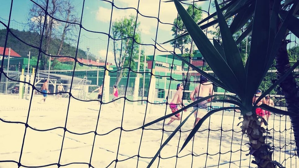 Beach volleyball game in Graz with net and palms. | © Mur Beach - Ingo Gruber