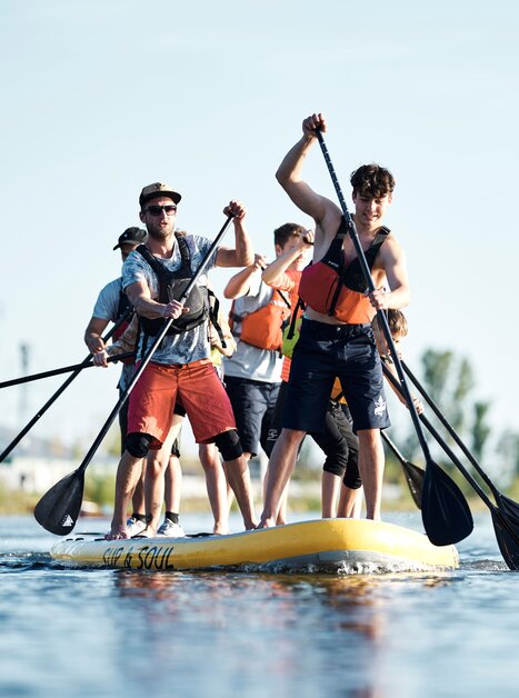 Gruppe von Menschen paddelt auf einem großen SUP im Wasser. | © Stadtstrand Graz - Stefan Leitner