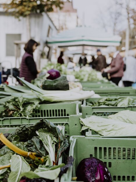 Gemüse steht auf einem Markt, mit Besuchern im Hintergrund. | © Nina Söntgerath - Reisehappen