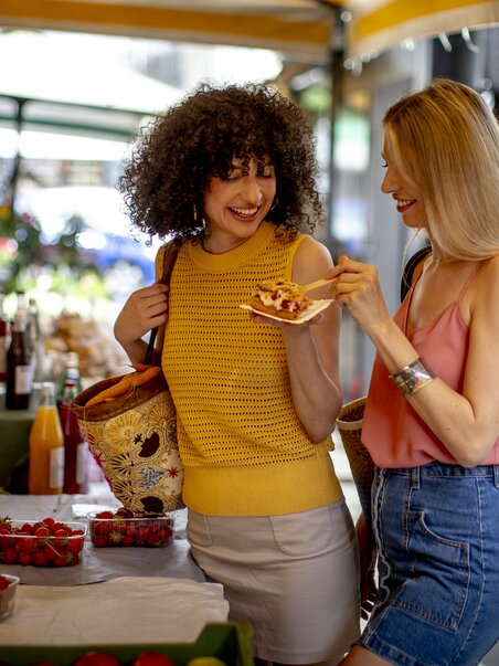 Zwei Frauen genießen frische Leckereien auf dem Markt. | © Graz Tourismus - Tom Lamm