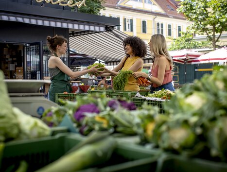 Two women buying fresh vegetables at the Kaiser Josef Market in Graz. | © Graz Tourismus - Tom Lamm