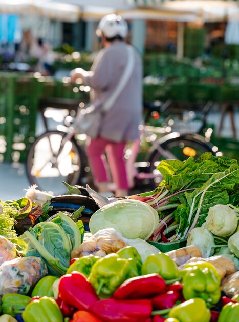 Bunte Gemüsevielfalt auf dem Bauernmarkt am Lendplatz in Graz - im Hintergrund eine Radfahrerin. | © Graz Tourismus - Mias Photoart