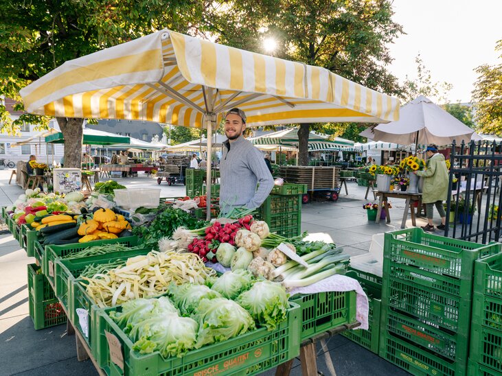 Vibrant market scene with fresh vegetables and seller in Graz. | © Graz Tourismus - Mias Photoart