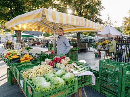 Lebendige Marktszene mit frischem Gemüse und Verkäufer in Graz. | © Graz Tourismus - Mias Photoart