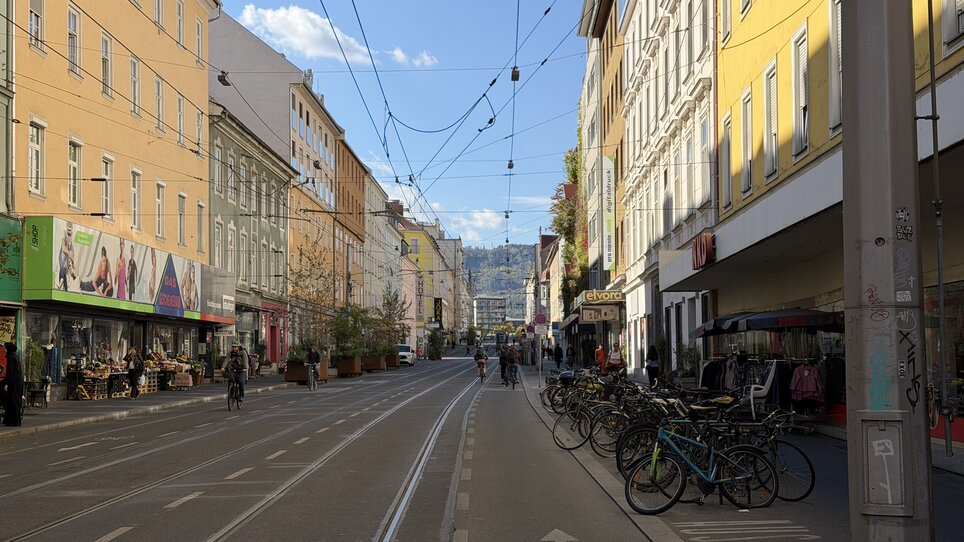 Eine belebte Straße in Graz mit Geschäften und Fahrrädern. | © Graz Tourismus