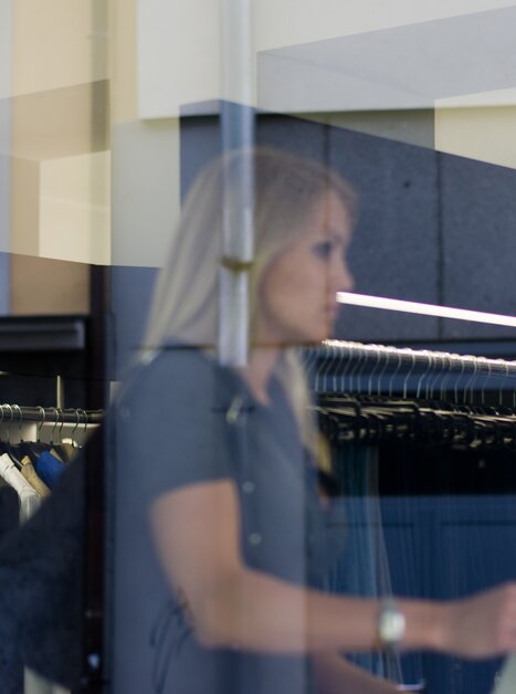 Riflesso di una donna in una vetrina, mentre fa shopping in un negozio di moda. | © Graz Tourismus - Hans Wiesenhofer