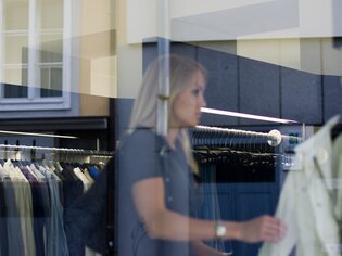 Riflesso di una donna in una vetrina, mentre fa shopping in un negozio di moda. | © Graz Tourismus - Hans Wiesenhofer