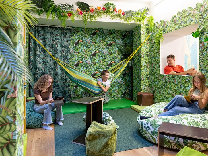 Ein Raum mit Pflanzenmuster, Hängematte und Jugendlichen, die entspannen. | © Kinderfreunde Steiermark