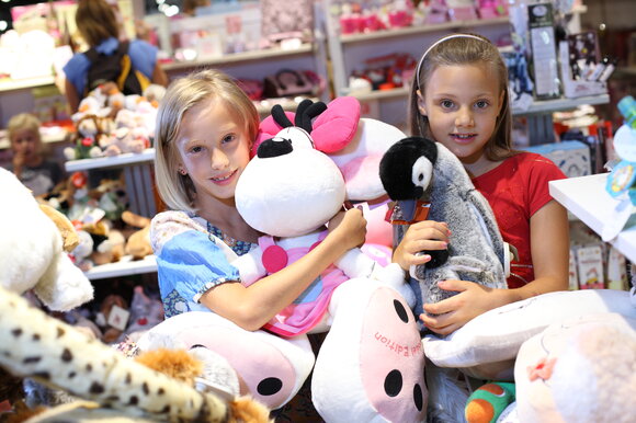 Zwei Mädchen umarmen große Plüschtiere in einem Geschäft. | © Graz Tourismus - Harry Schiffer