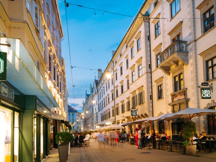 Lively Schmiedgasse in Graz at dusk with outdoor tables. | © Graz Tourismus - Mias Photoart