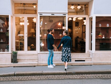 Coppia che si tiene per mano davanti a un negozio di antiquariato a Graz. | © Graz Tourismus