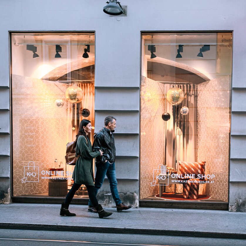 Two people walk past a store featuring modern furniture. | © Graz Tourismus