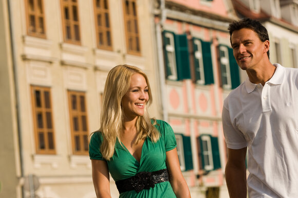 Couple walking through Graz with historic buildings in the background. | © Graz Tourismus - Hans Wiesenhofer