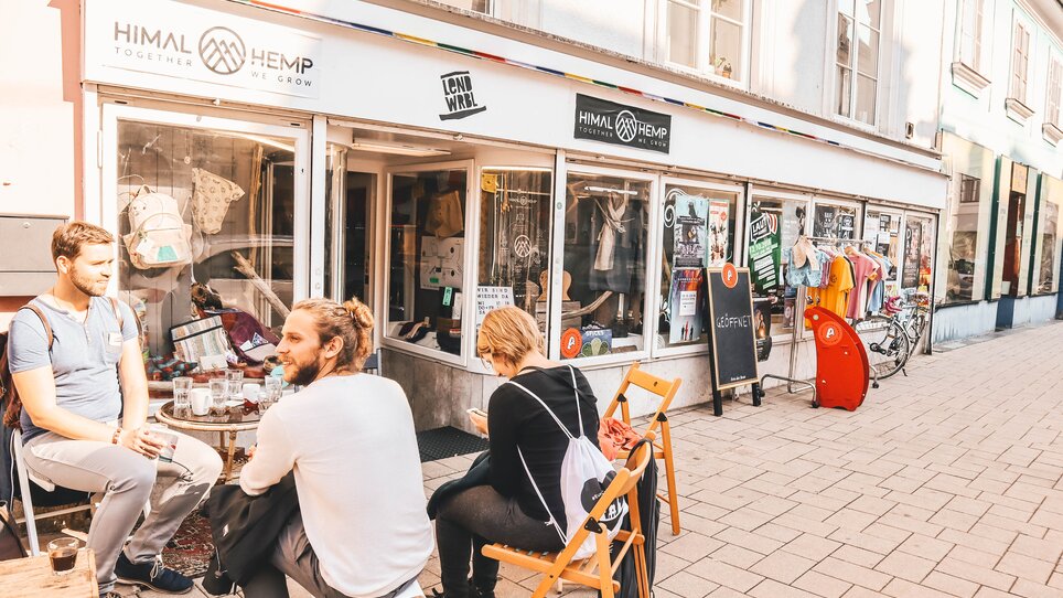 Drei Personen sitzen vor einem Geschäft im Lendviertel in Graz. | © Janet Newenham - Journalist On The Run