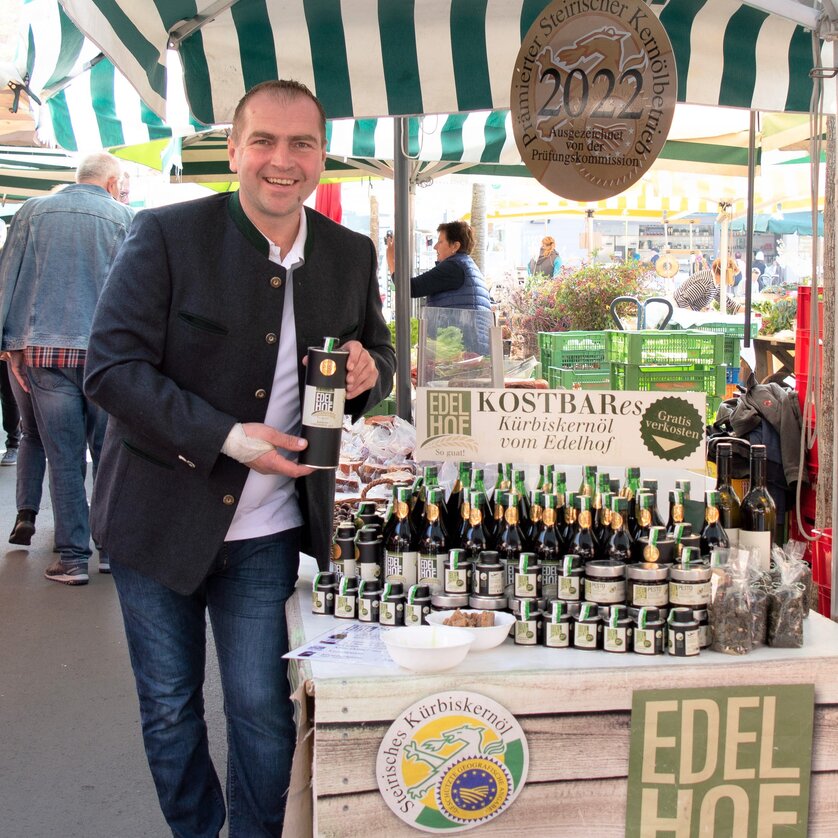 Uomo che vende olio di semi di zucca al mercato di Graz. | © Edelhof