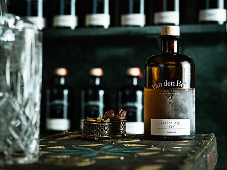 Flasche Van den Berg London Dry Gin auf einem Tisch neben einem Glas. | © EX KARELLY PHOTOGRAPHY