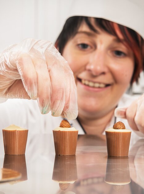 Frau dekoriert Pralinen in Eckhards Confiserie. | © Eckhards Confiserie I Graz