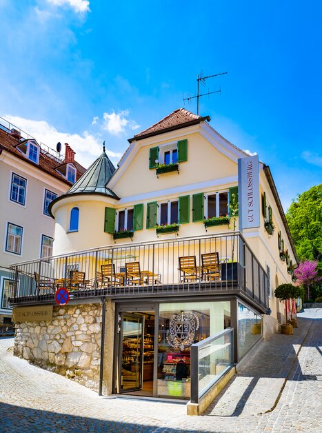 Ansicht des Geschäfts "Gut Schlossberg" in Graz - ein schönes Gebäude mit Terrasse und grünen Fensterläden. | © Gut Schlossberg