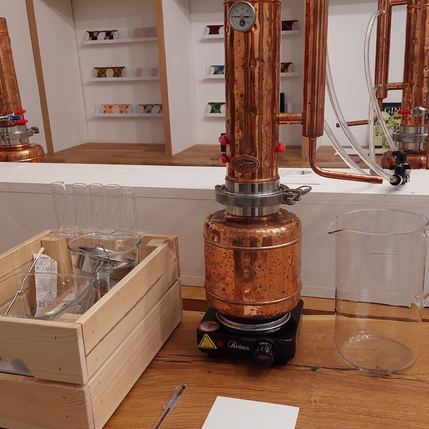 A copper distillery with glass containers and accessories in the background. | © The Ginery
