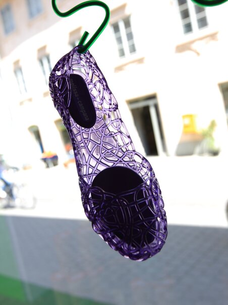 A purple shoe hangs from a string in a shop window in Graz. | © Graz Tourismus - Harry Schiffer