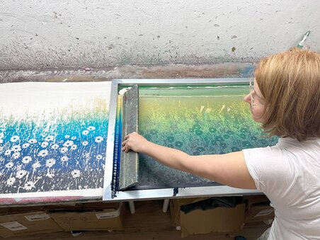 A person works on a color print in the studio, surrounded by art supplies. | © Peaces