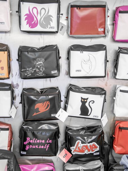 Verschiedene Taschen mit kreativen Designs, darunter Sprüche wie 'Believe in yourself' und Illustrationen. | © Tag