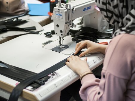 Eine Person näht an einer Juki Nähmaschine in einem kreativen Arbeitsumfeld. | © Tag