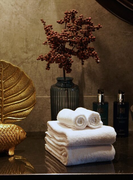 Elegant bathroom decor featuring golden accents and towels. | © Aiola Living