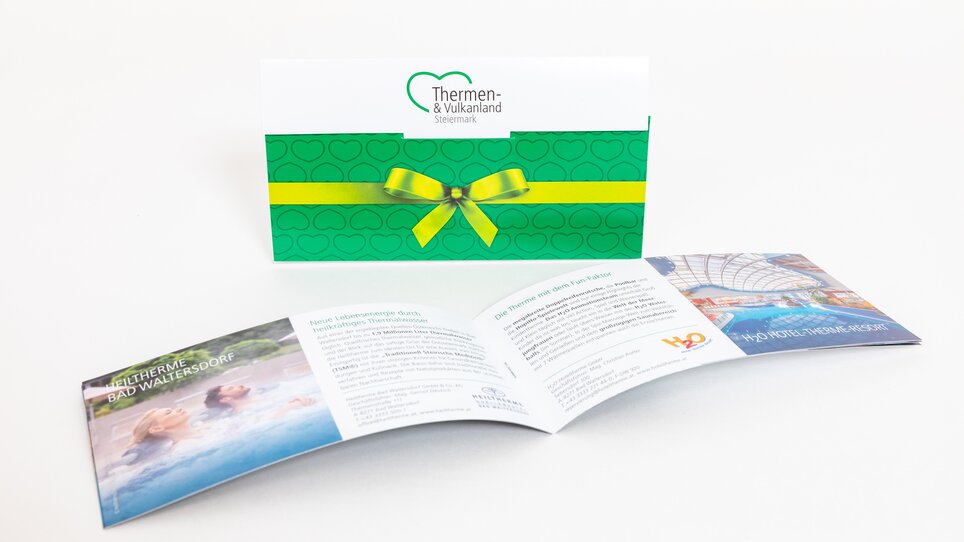 Offerta benessere da Thermen- & Vulkanland Steiermark su una brochure piegata. | © Graz Tourismus - Harry Schiffer