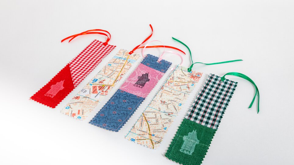 Cinque segnalibri in tessuto diversi, alcuni con motivi di mappe e altri a quadri. | © Graz Tourismus - Harry Schiffer