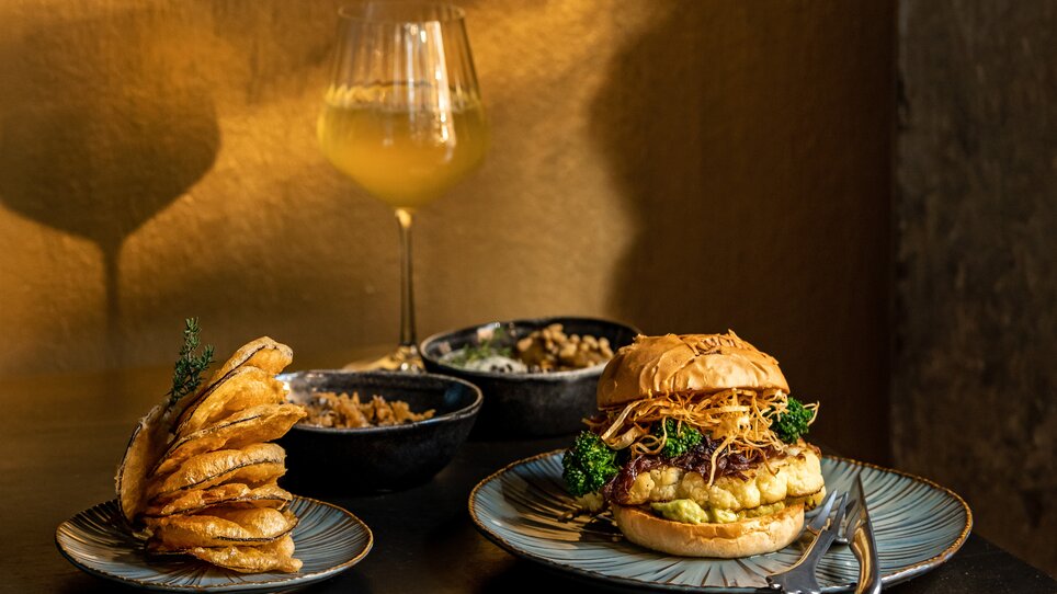 A delicious burger with sides and wine in a restaurant. | © Lucija Novak