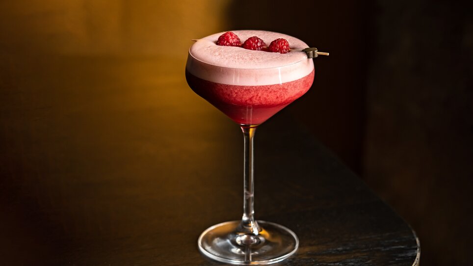 Cocktail with raspberries in an elegant glass, served in a stylish bar. | © Lucija Novak