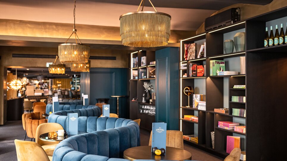 Cozy bar with modern decor in Graz, featuring bookshelves and stylish lamps. | © Lucija Novak