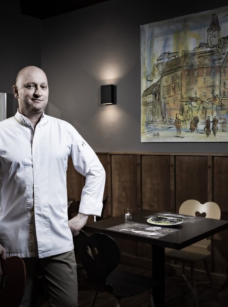 Uno chef è in un ristorante con un dipinto sullo sfondo. | © Graz Tourismus - Werner Krug