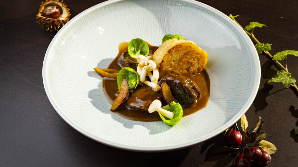 Game dish with mushrooms, vegetables, and sauce on a plate. | © Graz Tourismus - Werner Krug