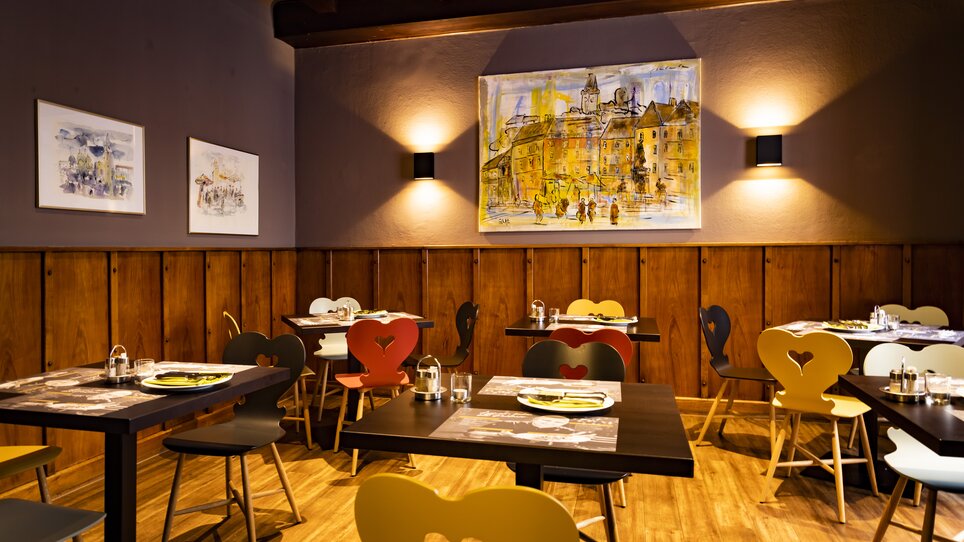Cozy restaurant with colorful chairs and wall art. | © Graz Tourismus - Werner Krug