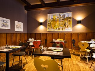 Cozy restaurant with colorful chairs and wall art. | © Graz Tourismus - Werner Krug