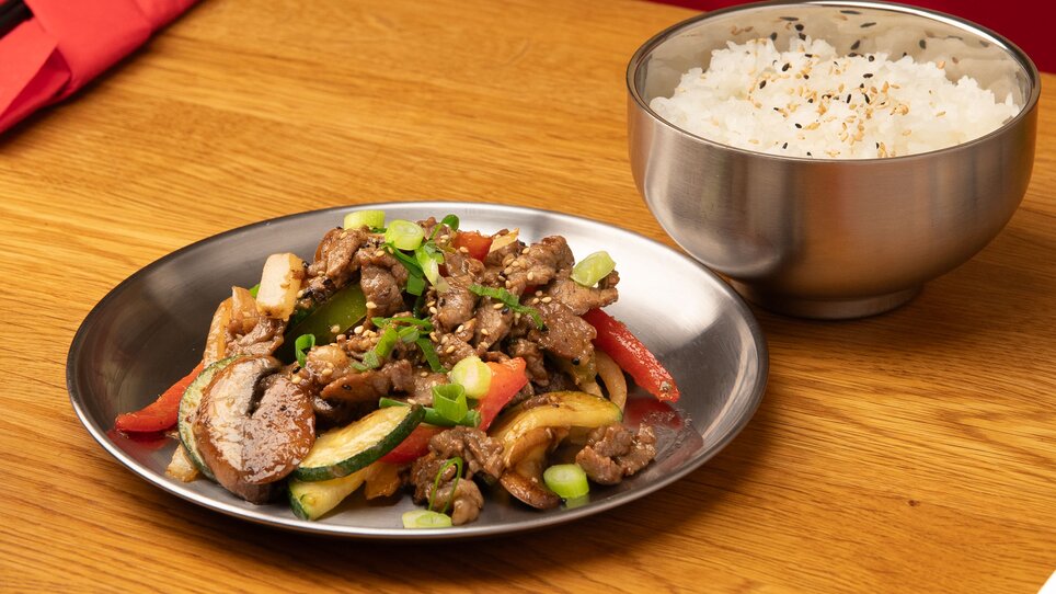 Un piatto di carne e verdure saltate accanto a una ciotola di riso. | © Gogi KG