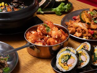 Piatto colorato di piatti asiatici su un tavolo, tra cui sushi e cibi saltati in padella. | © Gogi KG