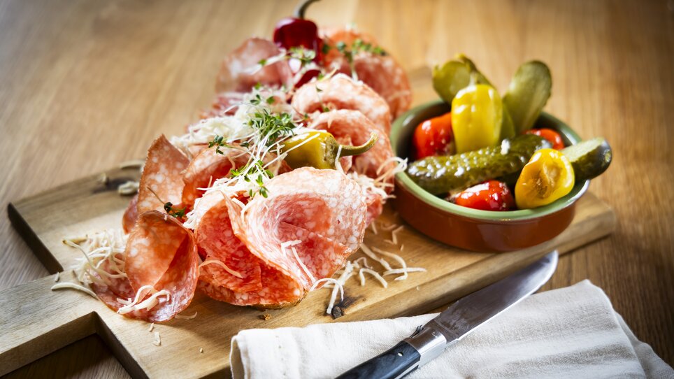 Platter with salami, cheese, pickles, and peppers on a wooden board. | © Kaiser Greissler - Werner Krug