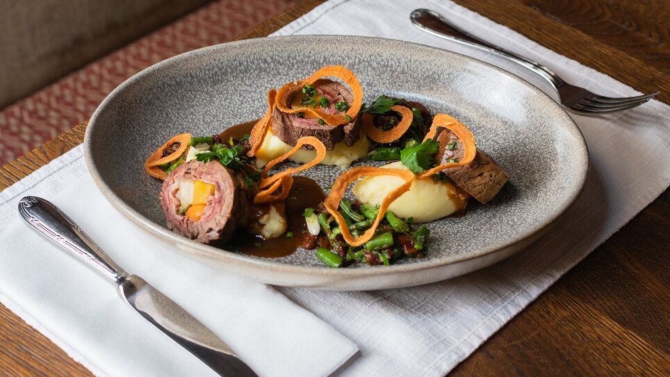 An elegant plate with meat, vegetables, and garnish in a restaurant. | © Jauk Katharina