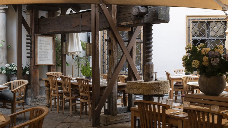Cozy restaurant courtyard with wooden tables and plants. | © Jauk Katharina