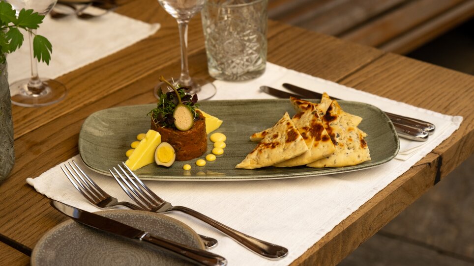 Beef tartare - elegantly decorated with vegetables and bread as side dishes on a plate. | © Benjamin Kern