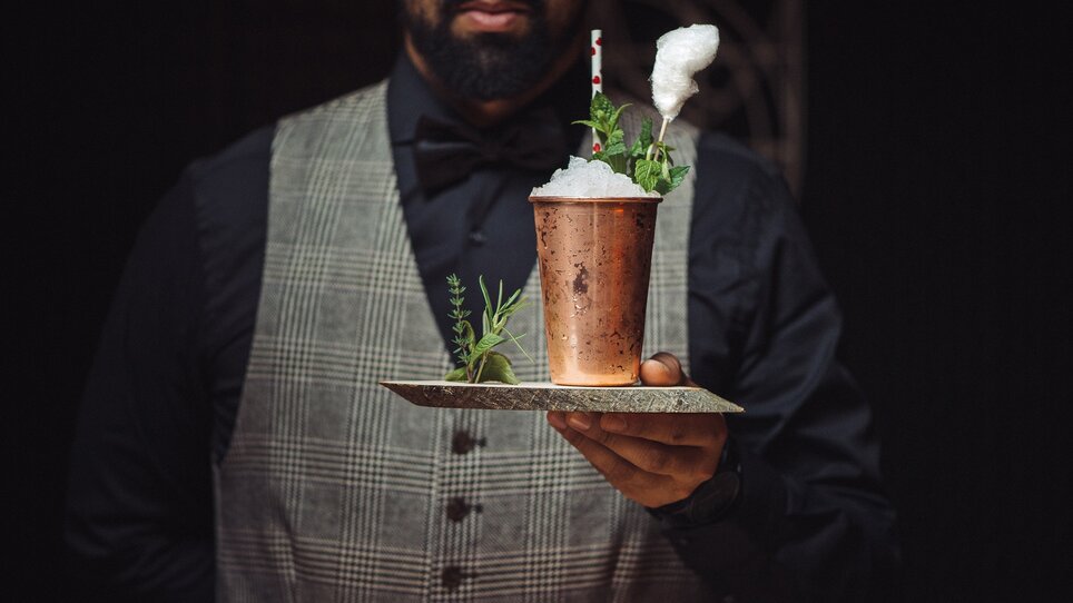 A bartender showcases an artistic cocktail topped with cotton candy. | © Landhauskeller