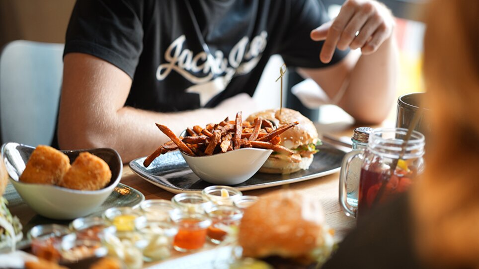 Ein köstlicher Burger mit einer Schale mit Süßkartoffel-Pommes auf einem Tisch. | © The Guardians