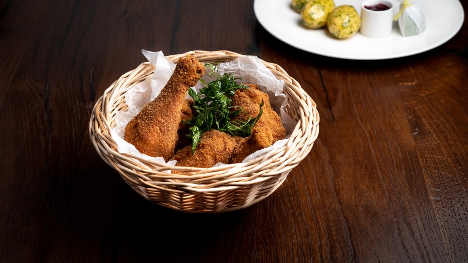 Baked chicken in a basket, parsley potatoes with cranberries on a plate next to it.  | © Mohrenwirt