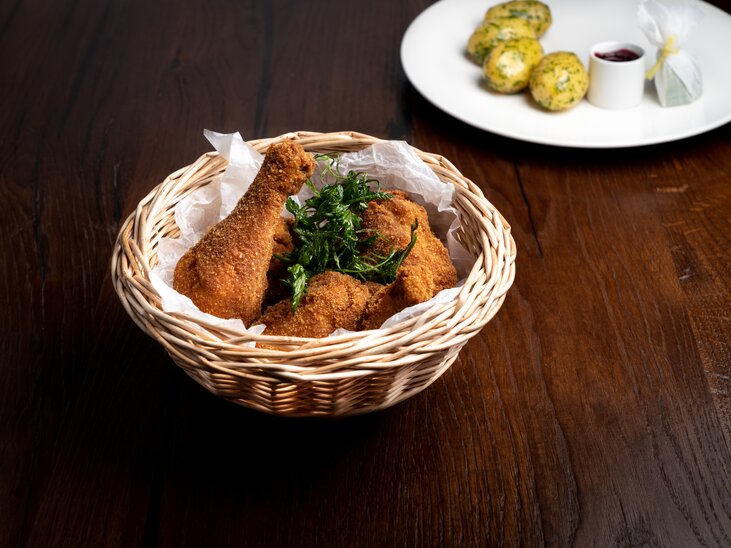 Backhendl in einem Korb, daneben Petersilienkartoffeln mit Preiselbeeren auf einem Teller.  | © Mohrenwirt